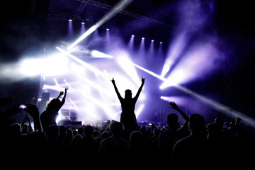 Silhouette of girl with raised hands enjoys the concert