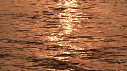 Wall Mural - Golden glisten of sunlight reflects on the sunrise sea surface. Sparkling sunlight over the calm water. Super slow motion footage.