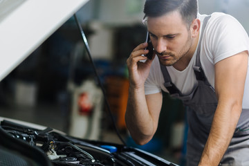 Auto mechanic talking on mobile phone in auto repair shop