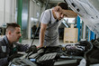 © Goran - Tired auto mechanics working on car engine in a workshop