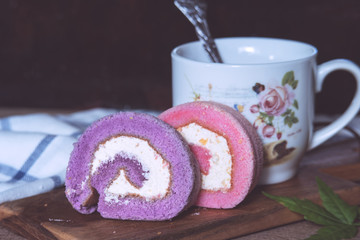 Purple and pink jam roll on cutting board, morning breakfast with jam roll and coffee.