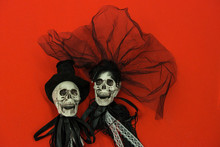Bride And Groom Skull Wedding Dresses Symbol Of The Day Of The Dead And Hallowed, Typical American Party, With Red Background