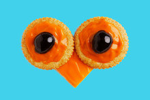 Salty Cracker With Cheddar Cheese And Black Olives In The Form Of An Owl's Eyes On A Cyan Background.