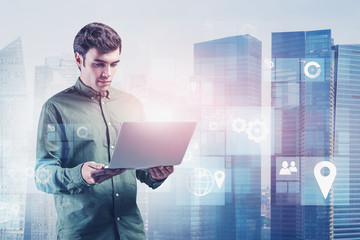 Engineer with laptop in city, digital interface