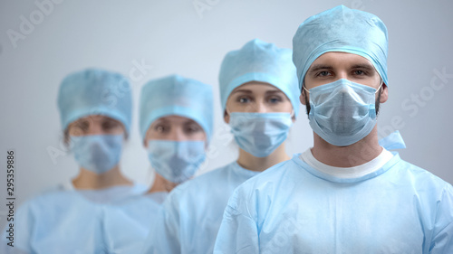 Fotomural Professional surgeon team in mask and uniform looking at camera, hospital work