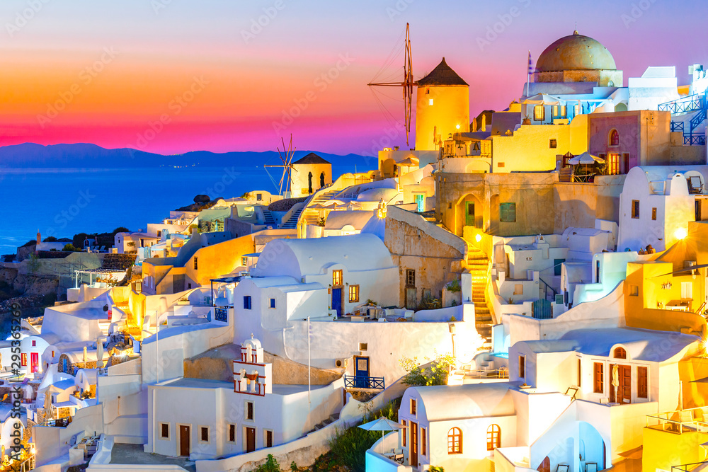 Oia town, Santorini island, Greece at sunset. Traditional and famous white houses and churches  with blue domes over the Caldera, Aegean sea. - obrazy, fototapety, plakaty 
