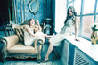© iordani - two pretty twin sister blond curly hairstyle girl in luxury house interior together, rich young people concept
