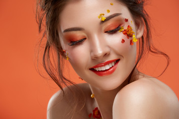 close-up of gorgeous woman with perfect smile and stylish orange mua looking down