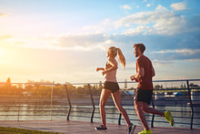 Modern Woman And Man Jogging / Exercising In Urban Surroundings Near The River.