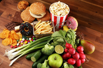 Wall Mural - healthy or unhealthy food. Concept photo of healthy and unhealthy food. Fruits and vegetables vs donuts and fast food