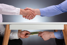 Two Businessmen Shaking Hands And Receiving Bribe