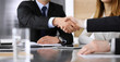 © Iryna - Businessman shaking hands with his colleague or partner above the glass desk in modern office, close-up. Unknown business people at meeting. Teamwork, partnership and handshake concept