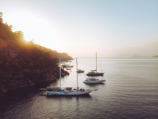 Wall Mural - Evening sunset on the mediterranean sea. Luxury yachts lined up along the Turkish coastline, islands can be seen in the distant background. Beautiful scene shot aerially from a drone.