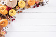 Top view of Autumn maple leaves with Pumpkin and red berries on white wooden background. Thanksgiving day concept.