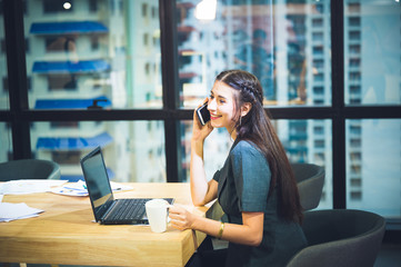 Beautiful business women workink with mobile phone and computer at the skyline office