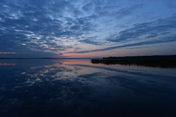 Wall Mural - Twilight blue sky in clouds reflected on lake water at sunset in the autumn evening