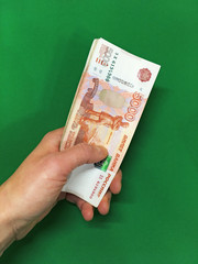 Money, rubles in hand a bundle of green on isolated background. Russian banknotes one thousand, five thousand, two thousand