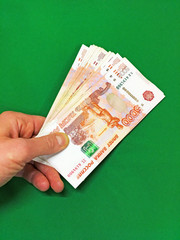 Money, rubles in hand a bundle of green on isolated background. Russian banknotes one thousand, five thousand, two thousand