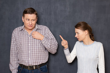 Angry dissatisfied short woman is rebuking scared upset tall man