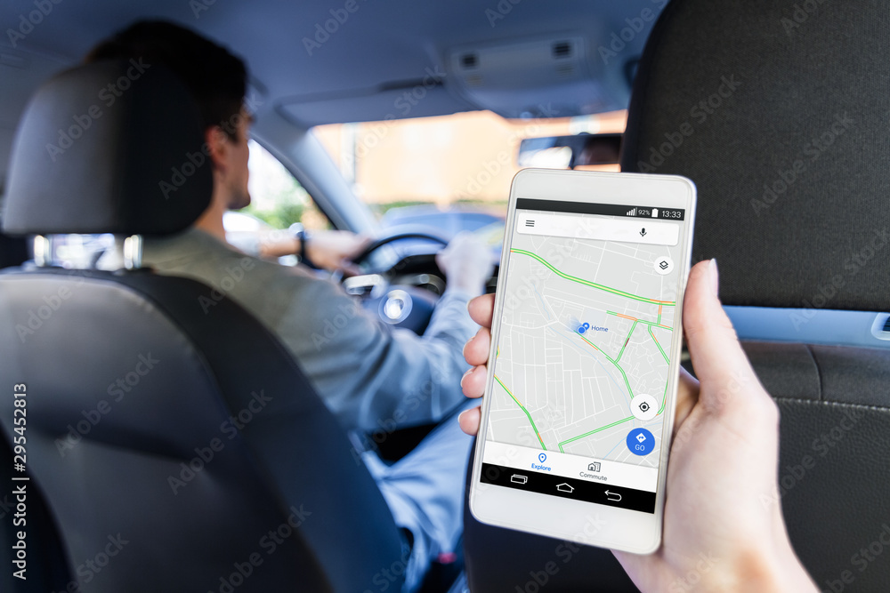 Closeup female hand is holding smartphone with online map on screen, shows way to home. Woman is riding on back seat of automobile car. Taxi booking application, mobile GPS navigator concept. - obrazy, fototapety, plakaty 