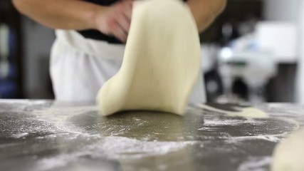 Wall Mural - Chef forming the dough on a floured surface and kneading it with his hands.