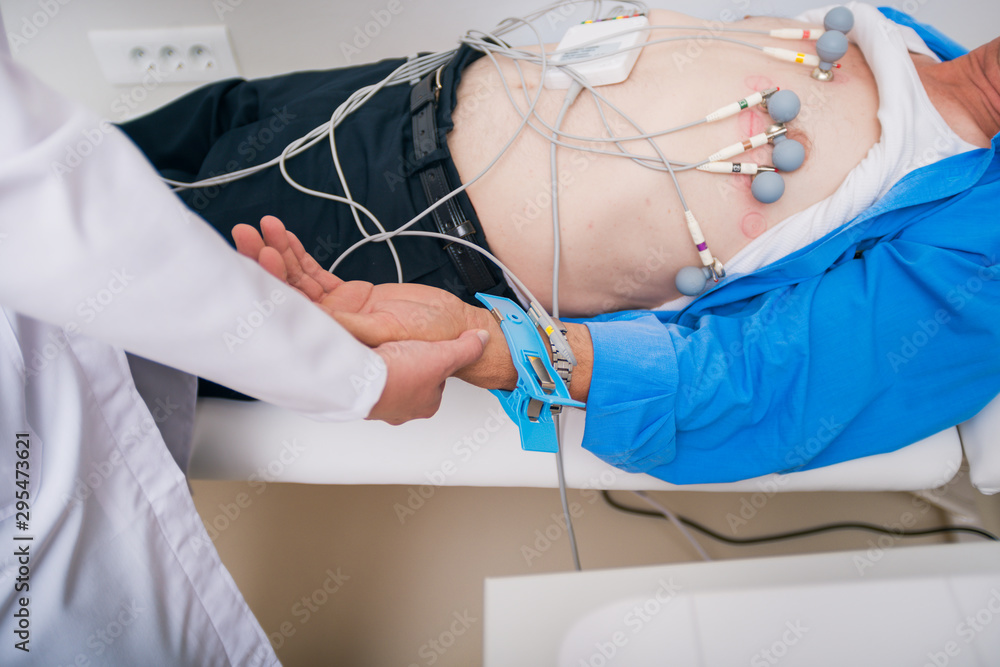 Doctor ( cardiologist ) is attaching vacuum sensors to an elder ...