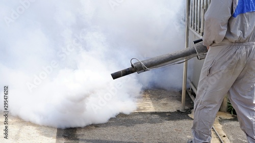 Part of of health personnal worker using fogging machine spraying chemical to eliminate mosquitoes and prevent dengue fever at general location in community
