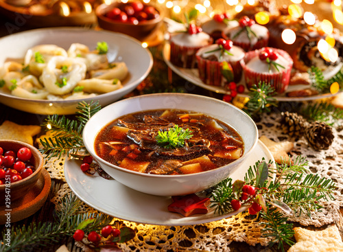 Christmas mushroom soup, a traditional vegetarian  mushroom soup made with dried forest mushrooms in a ceramik plate on a festive table. Polish Christmas dinner