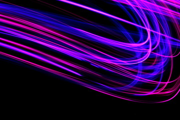 Wall Mural - Long exposure photograph of pink and purple neon colour in an abstract swirl, parallel lines pattern against a black background. Light painting photography.