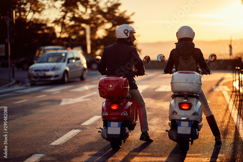 Fotomural Couple riding motor scooter on road at sunset.
