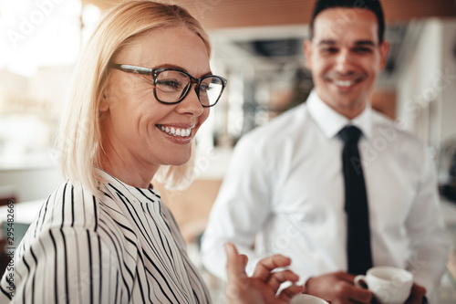 Fotomural Smiling businesswoman talking with colleagues over coffee in an
