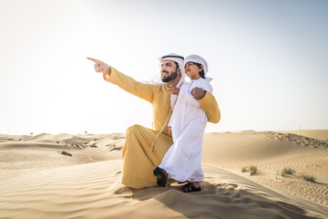 Wall Mural - Arabian man and son playing in the desert