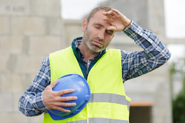 builder man with tired face wipes forehead