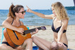 © auremar - beautiful women having fun playing guitar on the beach
