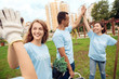 © Viktoriia - Volunteering. Young people volunteers outdoors planting trees giving high five successful close-up