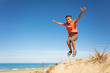 Cute boy jump on the sand dune beach with hands up