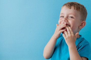 Wall Mural - Little Boy Holding and eating an Banana on blue background, food, diet and healthy eating concept