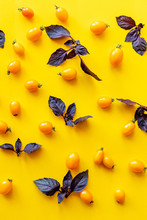 Yellow Mini Tomatoes And Purple Basil Leaves On Yellow Background
