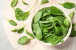Bowl of fresh green healthy spinach on table, flat lay