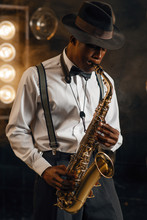Black Jazzman In Hat Plays The Saxophone On Stage