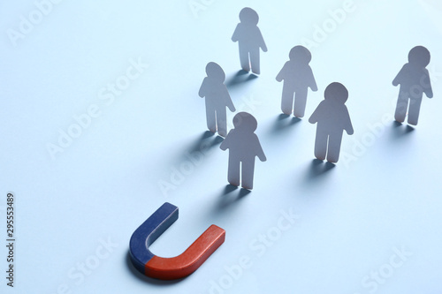 Cuadros en Lienzo Magnet attracting paper people on light blue background, space for text
