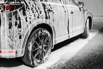 Luxury automobile covered with foam at car wash, closeup