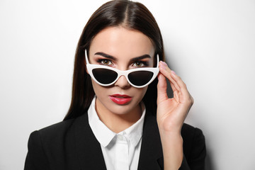 Canvas Print - Young businesswoman in stylish sunglasses on light background