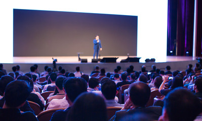 Seminar presenter at corporate conference giving speech. Speaker giving lecture to business audience. Entrepreneur forum executive manager leading discussion in hall during company training event. 