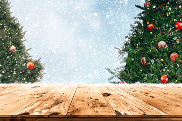 Wall Mural - top of empty wood table with beautiful christmas tree and snowfall backdrop. ready for your product 