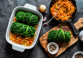 Making vegetarian delicious lunch - roasted savoy cabbage stuffed spicy bulgur. Savoy cabbage bulgur rolls in baking pan on a dark background, top view