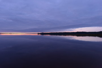 Wall Mural - Twilight glow in the blue sky at sunset from the horizon above the water to the shoreline of the lake
