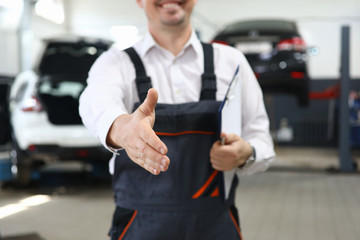 Focus on smart man hand reaching for firm handshake with someone and holding important paper folder with information about different autos. Machinery repairman concept