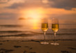 Two glasses of champagne on sandy beach  in beautiful sunset