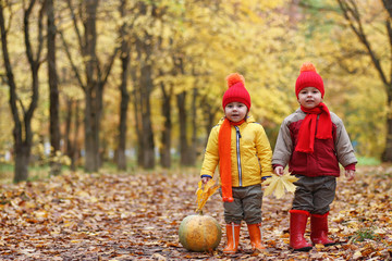 Children are walking in nature. Twilight kids are walking around the park. Brother with sister in autumn city park in leaf fall.